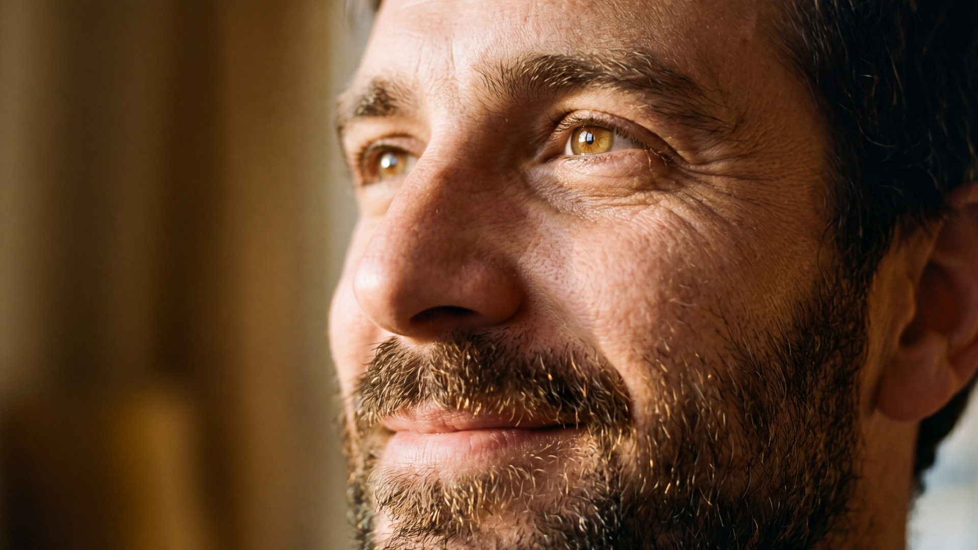 A close-up of a smiling white man with dark brown hair and a beard in his 40s