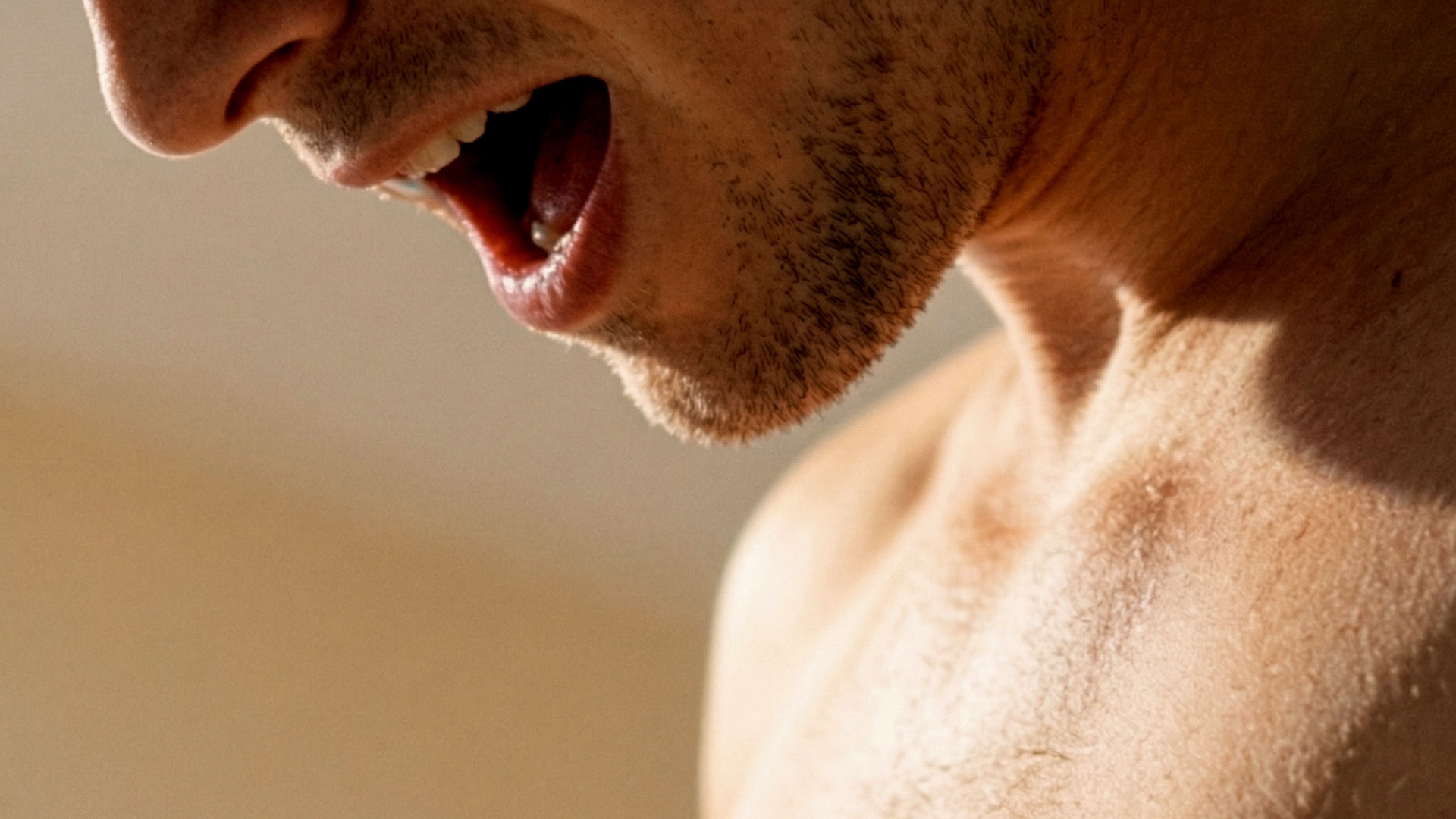 Close-up of a shirtless man with his mouth open in pleasure