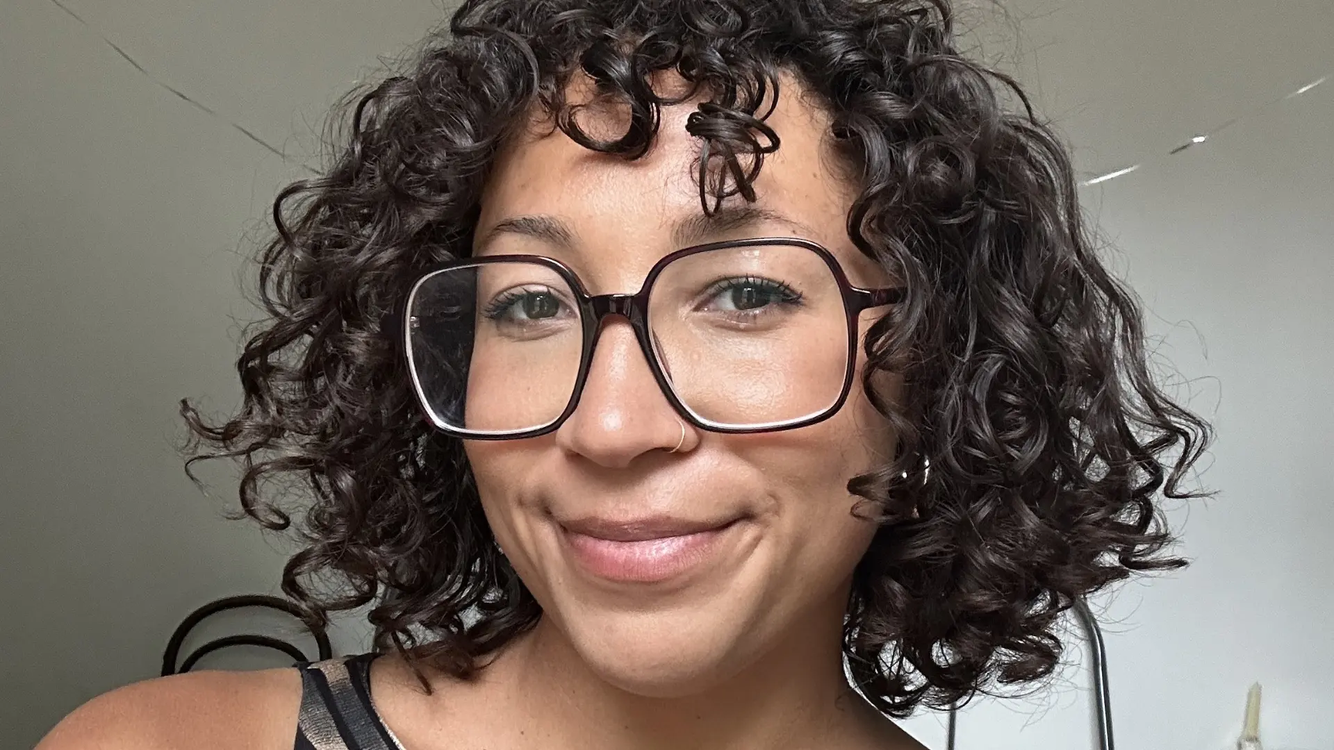 Sunny smiling at the camera, with curly hair and large glasses