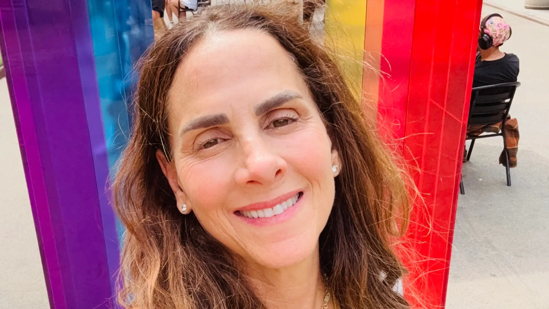 Susan smiling in front of a colourful rainbow installation