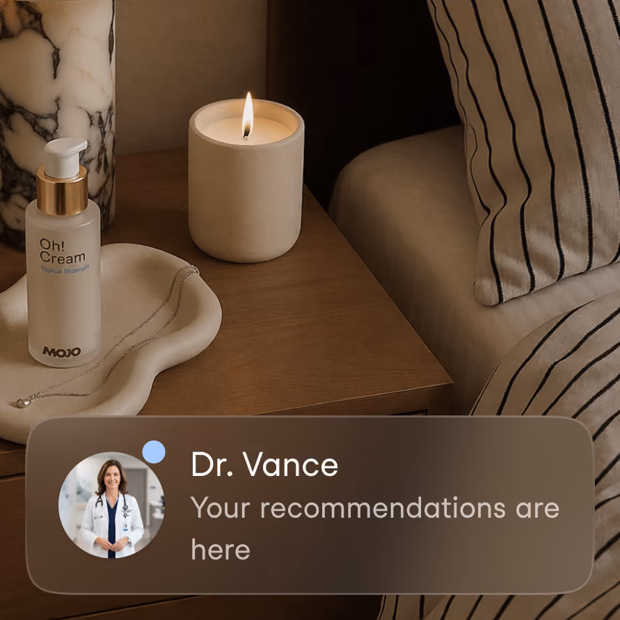 A bedside table with a lit candle, a white tray holding a silver necklace and a bottle labeled 'Oh! Cream MOJO', next to a striped pillow on a bed, with an overlay notification showing a female doctor and the text 'Dr. Vance Your recommendations are here.'